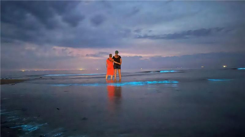 Bäume umgestürzt, Camp geräumt - aber auch Naturschauspiel Im flachen Wasser schauen zwei Frauen am Nordstrand von Norderney aufs Meer.