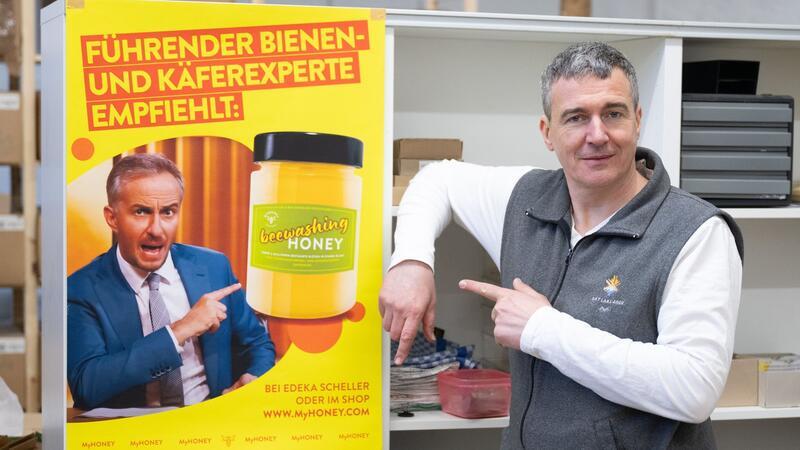 Imker Rico Heinzig neben einem Plakat mit dem Foto des Moderators Jan Böhmermann.