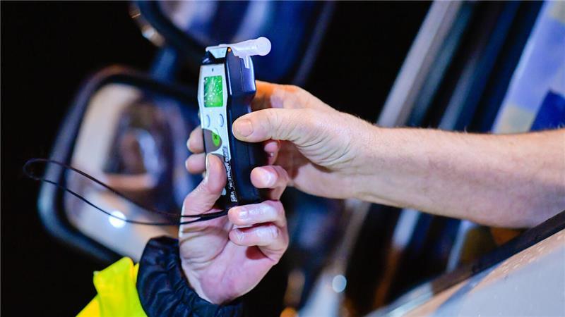 Immer wieder         Ein Autofahrer übergibt einem Polizisten ein Alkoholtestgerät.