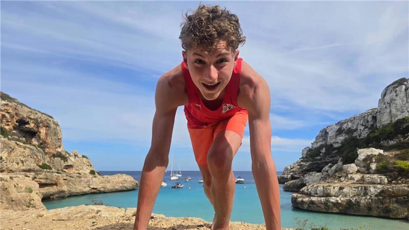 Elias Frank in Startposition eines Läufers auf einem Felsen, dahinter das Meer.