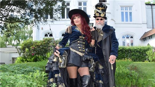 Imposant gekleidet besuchen Dagmar und Jürgen Herzer aus dem Saarland das Steampunk-Festival in Buxtehude. Die Steampunk-Darstellerin trägt eine silberne Drachenfigur unterm Rock.