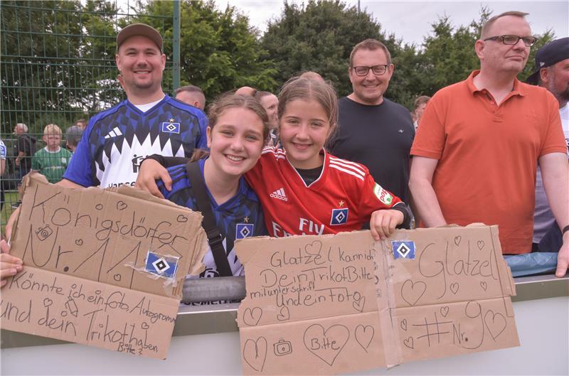 Zwei Mädchen und HSV-Fans haben auf Pappen die Wünsche an ihre Lieblingsspieler aufgeschrieben.