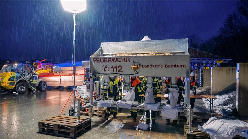 In Schlüsselfeld im Landkreis Bamberg befüllen Feuerwehrleute Sandsäcke.