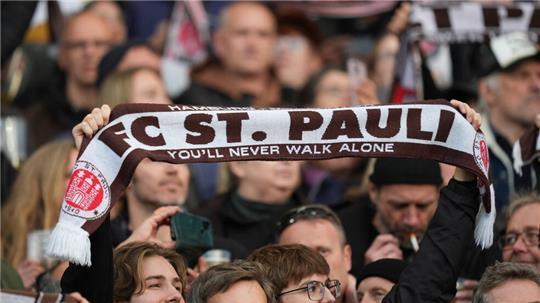St. Pauli-Fans jubeln auf der Tribüne der Mannschaft zu.