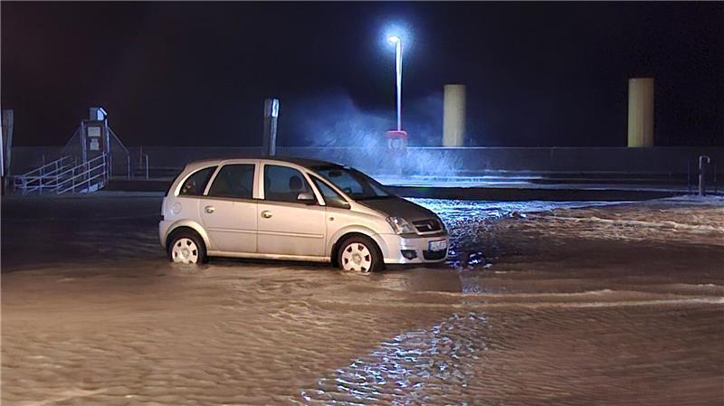 In Wilhelmshaven steht ein Auto auf einem überfluteten Parkplatz.