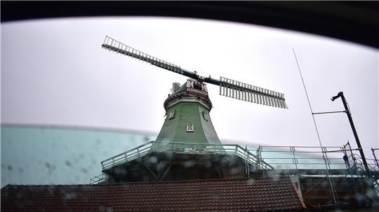 Die Windmühle Venti Amica fotografiert aus einer Autoscheibe mit Regentropfen an der Fensterscheibe.