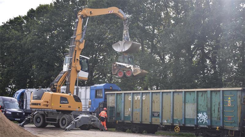 Ein staubiger und riskanter Job: Waldkalkung von Fredenbeck bis Beverstedt In alle Ecken der Waggons kommt der Umschlagbagger nicht. In den Waggon hebt er dafür einen kleinen weißen Kompaktlader, auch Bobcat (englisch für Rotluchs) genannt, weil er wie die Kleinkatze als Namensgeber robust, schnell und wendig ist. Einen kleinen Rest fegt der Mitarbeiter selbst aus.