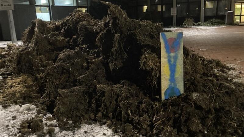 In dem Misthaufen steckt eine Holzlatte mit aufgemalter Ampel.