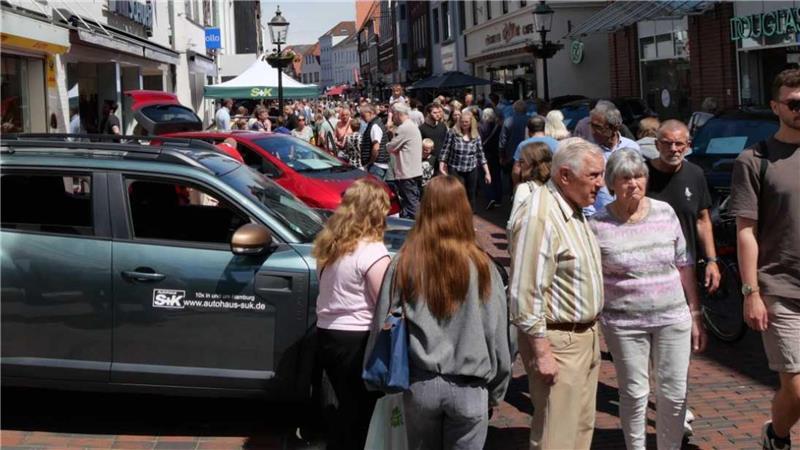 In der langen Straße herrschte reger Betrieb zwischen offenen Geschäften und Ausstellungsfahrzeugen.