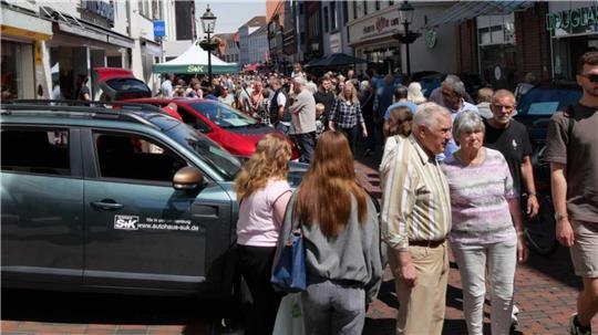 In der langen Straße herrschte reger Betrieb zwischen offenen Geschäften und Ausstellungsfahrzeugen.