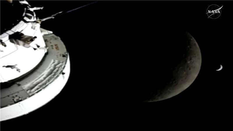 In diesem Bild aus einem von der NASA zur Verfügung gestellten Video sind die „Orion“-Raumkapsel, der Mond und die Erde (r) von einer Kamera aus zu sehen, während die „Artemis 2“-Besatzung und das Raumschiff weiter in den Weltraum vordringen.