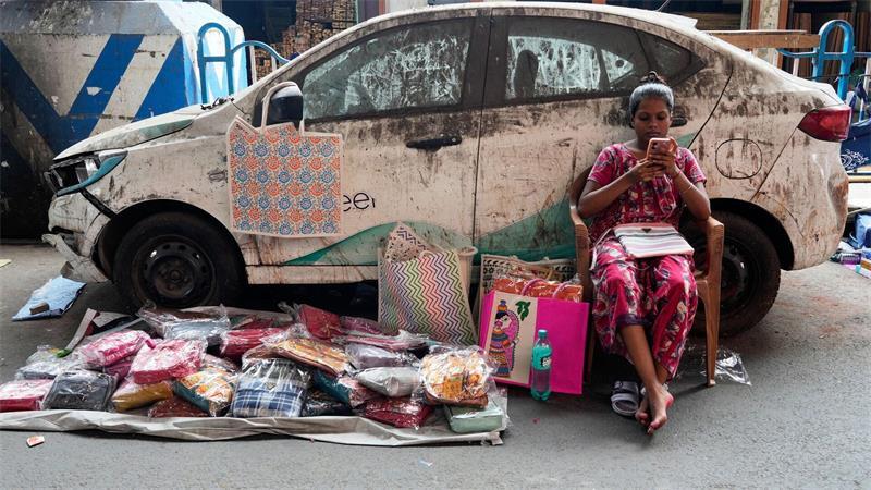 Indien - Verkäuferin mit Handy verkauft Taschen
