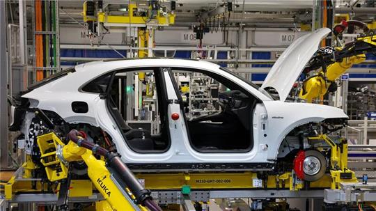 Industrieroboter arbeiten an einem vollelektrischen Porsche Macan.