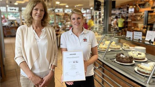 Ines Utecht (links) vom Tourismusverband und Carola Matthies präsentieren die Zertifizierungsurkunde "Reisen für alle" im barrierefreien Café des Obsthofs in Jork-Borstel.