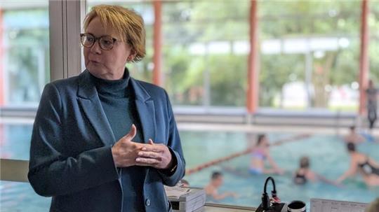 Innenministerin Daniela Behrens lässt sich die Kehdinger Welle zeigen, während im Hintergrund eine Schulklasse Schwimmunterricht hat.