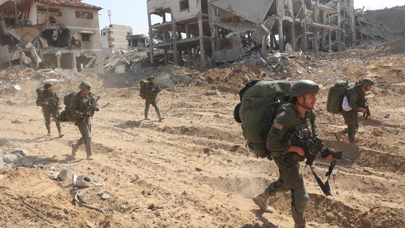 Gaza-Krieg: Neuer Anlauf im Ringen um Feuerpause Israelische Soldaten marschieren während einer Bodenoffensive durch den Ort.
