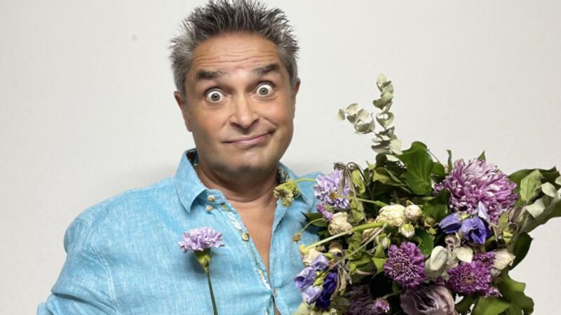 Roberto Capitoni schaut mit aufgerissenen Augen und hat einen Blumenstrauß in der Hand