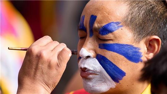 Jahrestag des Aufstandes gegen die chinesische Besatzung in Tibet: Ein tibetischer Mönch im Exil lässt sein Gesicht in einem Tempel in Indien in den tibetischen Farben bemalen.