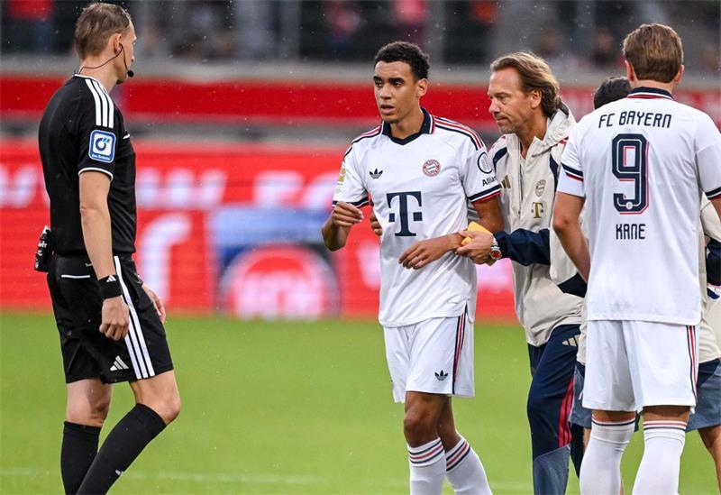 Jamal Musiala (l, FC Bayern München) verlässt den Platz in Begleitung. Er war aufgrund von Absencen in zwei Testspielen zusammengebrochen.