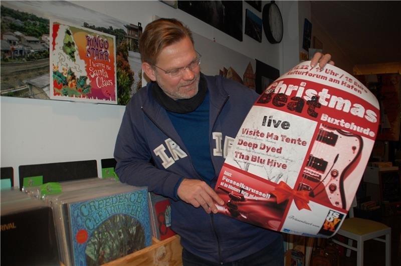 Jan Iso Jürgens zeigt in seinem Schallplattengeschäft das Plakat zum Christmas Beat. Foto: Laudien