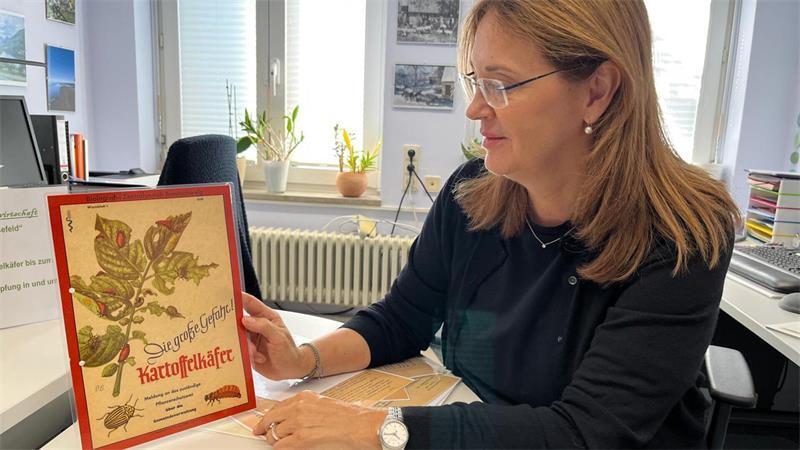 Jenny von Rönn, Mitarbeiterin des Samtgemeindearchivs Harsefeld, mit einem alten Plakat über Schädlinge.