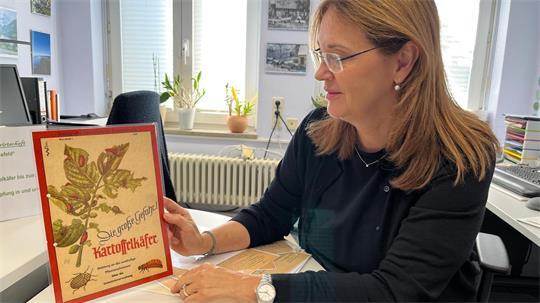 Jenny von Rönn, Mitarbeiterin des Samtgemeindearchivs Harsefeld, mit einem alten Plakat über Schädlinge.