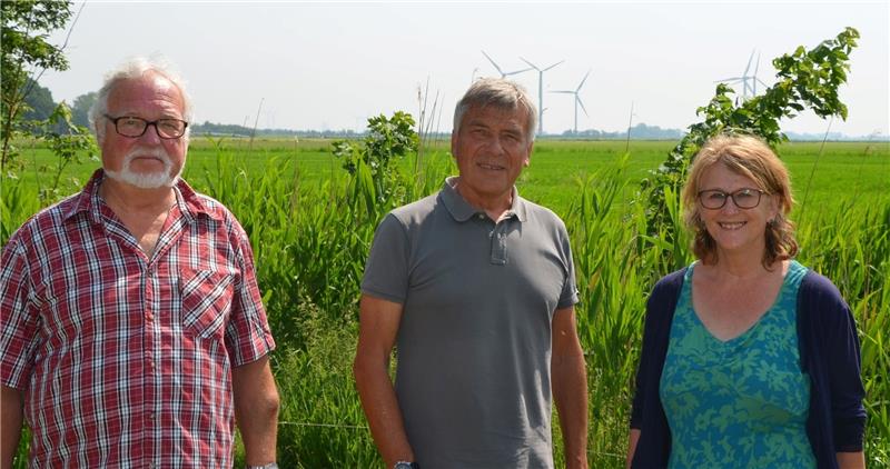 Jens Müller, Gabriele Kuhne und Axel Hebestreit von der Bürgerinitiative halten den Standort an der Oste für komplett ungeeignet. Im Hintergrund ist ein alter Nordkehdinger Windpark zu sehen. Foto von Allwörden
