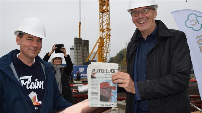 Jens Saß (rechts), geschäftsführender Gesellschafter des Unternehmens Implantcast, befüllt bei der Grundsteinlegung die Zeitkapsel mit der aktuellen TAGEBLATT-Ausgabe.