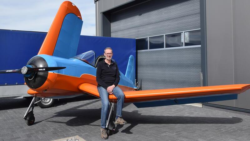 Jörg Hollmann sitzt auf dem Knickflügel der Corsair. Der zum Transport konstruierte Anhänger enthält Solarmodule, die den Elektroantrieb des Flugzeugs während des Transports aufladen.