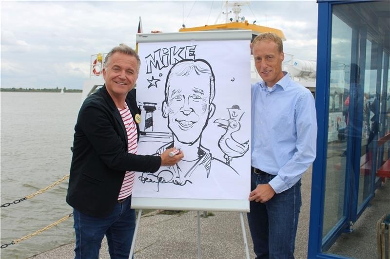 Jörg Knör und der Drochterser Bürgermeister Mike Eckhoff mit der Karikatur, die Knör live am Fähranleger Stadersand zeichnete. Fotos: Frank