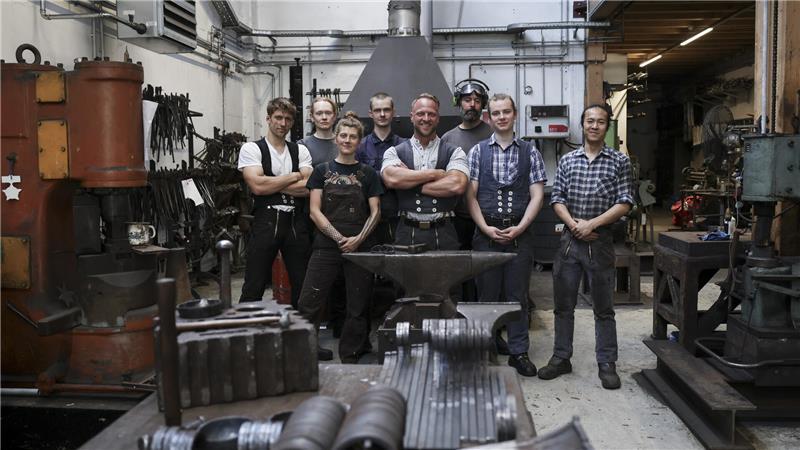 Johannes Rienhoff (M), Schmiedemeister und Inhaber der Schmiede Lehmann, steht mit seinem Team (l-r) David Giesinger, Auszubildender, Denis Hamann, Praktikant, Naima Waage, Auszubildende, Arvid Rabe, Auszubildender, Michael Oppenhorst, Geselle, David Sgaga, Auszubildender, und Alexander Sun, Auszubildender, in der Werkstatt der Schmiede Lehmann in Hamburg-Altona.