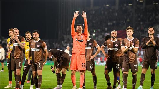 Sankt Paulis Torhüter Nikola Vasilj (M) reckt nach dem 0:0 gegen Leipzig die Hände in Richtung der Fans nach oben. 