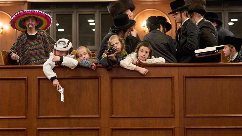 Jüdische ultraorthodoxe Männer und Kinder, von denen einige Kostüme tragen, halten sich in einer Synagoge in Jerusalem im Rahmen des Purimfestes auf.
