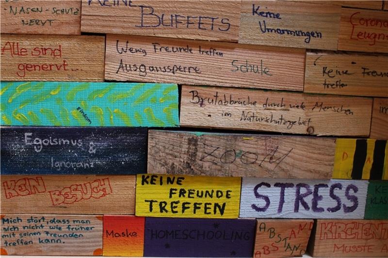 Jugendliche haben Holzklötze gestaltet, die zeigen, was sie in der Pandemie am meisten belastet . Diese werden in der Buxtehuder St.-Paulus-Kirche zu einer „Corona-Mauer“ aufgestapelt. Foto: Frank