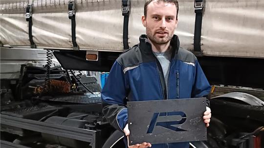 Julian Roß mit dem Firmen-Logo des Unternehmens Rancke Fahrzeugbau.