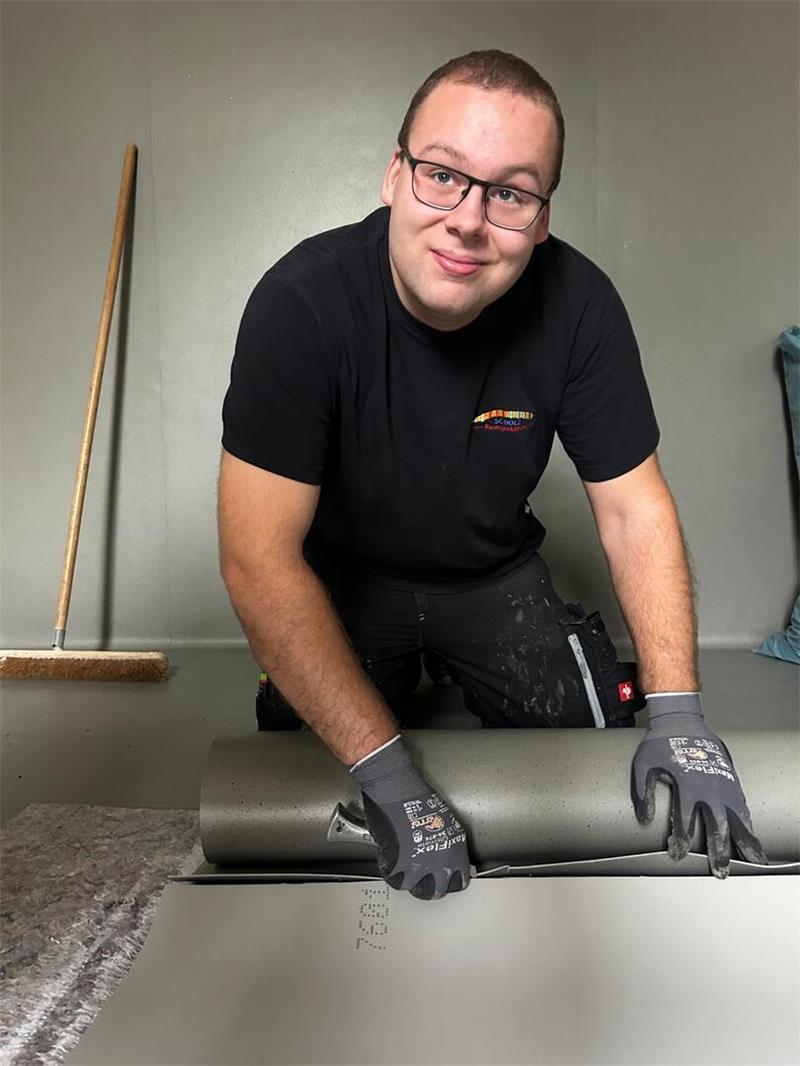 Neuer Höhepunkt an Himmelpfortens Grundschule Julian Schnarje von der Firma Scholz aus Stade schneidet Kautschuk passend. Statt Fliesen wird das weiche Material auf dem Boden und an der Wand der Sanitärräume verlegt.