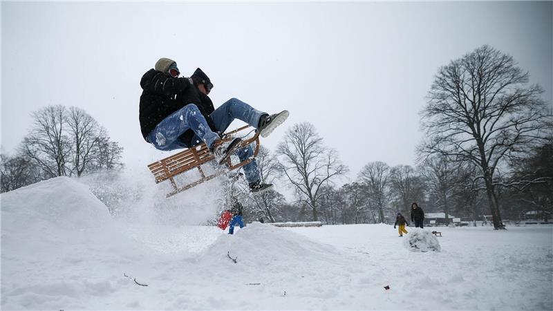 Junge Schlittenfahrer springen über eine Schanze im tief verschneiten Hamburger Schanzenpark. (Archivbild)