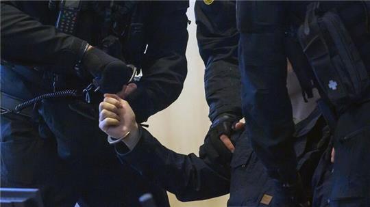 Justizbeamte nehmen dem Angeklagten Stephan Balliet im Gerichtssaal die Handschellen ab.