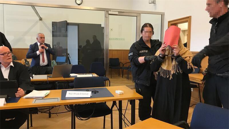Justizmitarbeiter führen die Hauptangeklagte in den Schwurgerichtssaal.