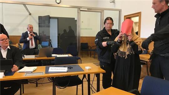 Justizmitarbeiter führen die Hauptangeklagte in den Schwurgerichtssaal.