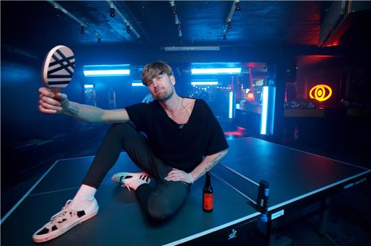 Kai Kaden, Mit-Veranstalter der wöchentlichen Veranstaltung „Topspin Techno“ im Solar Club im Baalsaal auf der Reeperbahn, sitzt auf einer Tischtennisplatte. Foto: Marcus Brandt/dpa