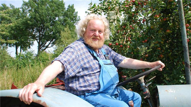 Kann wieder Gas geben: Eckart Brandt mäht mit seinem Trecker zwischen den Baumreihen - als Kulisse dient hier die alte Apfelsorte „Schöner aus Hadeln“.