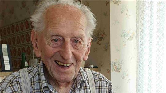 Karl Haidle sitzt an seinem 104. Geburtstag an einem Tisch und liest Zeitung.