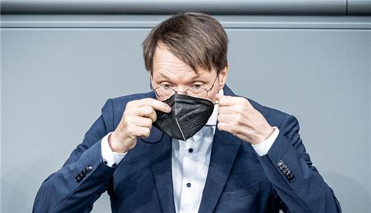 Karl Lauterbach (SPD), Bundesminister für Gesundheit, setzt im Bundestag in der Debatte zur Abstimmung zum COVID-19 Bevölkerungsschutzseine Maske auf. Foto: Michael Kappeler/dpa