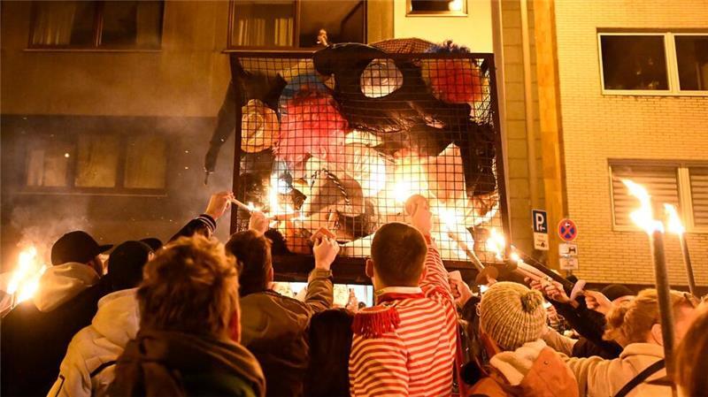 Karnevalisten in Köln zündeln ihre „Nubbel“ in dem Gefängniskäfig an.