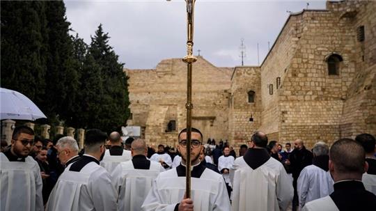 Katholische Geistliche gehen am Heiligabend in Bethlehem im Westjordanland in einer Prozession neben der Geburtskirche.