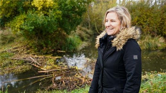 Katrin Eder (Grüne), rheinland-pfälzische Umweltministerin, steht bei einer vor einem von Bibern gebauten Damm.