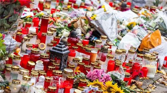 Kerzen und Blumen liegen vor dem Eingang der Waldbachschule.