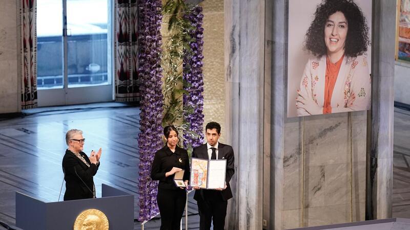 Kiana (l) und Ali Rahmani halten die Medaille und die Urkunde während der Verleihung des Friedensnobelpreises 2023 im Rathaus von Oslo. Die Zwillinge nehmen den Friedensnobelpreis stellvertretend für ihre inhaftierte Mutter entgegen.
