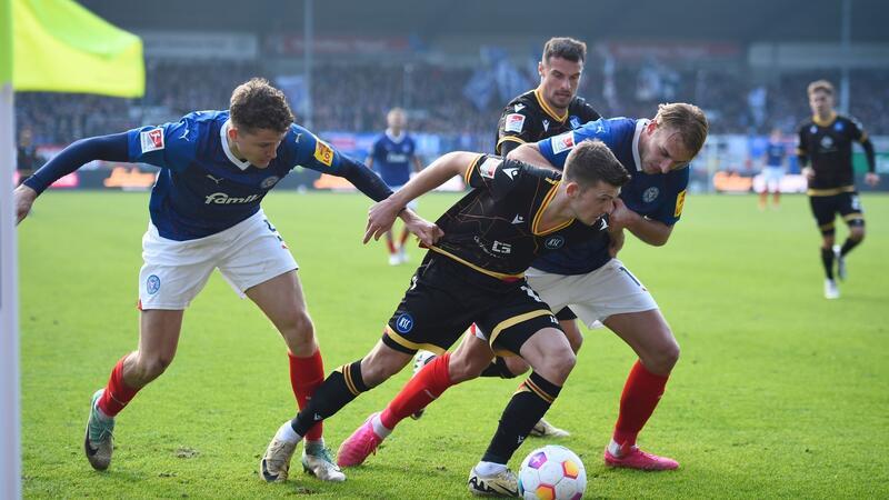 Probleme auch mit Baumgart größer: „Muss deutlicher werden“ Kiels Benedikt Pichler (li) und Timo Becker (r) versuchen dem Karlsruher Marvin Wanitzek (M) den Ball abzunehmen.